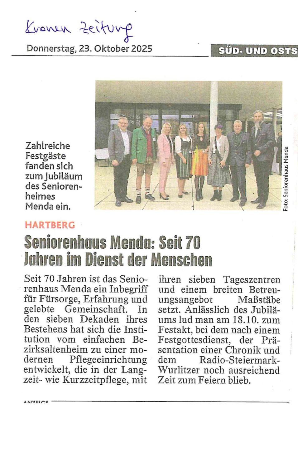 Eine Gruppe von acht Personen steht in einer Reihe, gekleidet in formeller und halbformeller Kleidung, und lächelt für ein Foto bei einer Feier vor einem Gebäude. Eine Bildunterschrift und ein Artikel beschreiben das 70-jährige Bestehen einer Seniorenresidenz.
