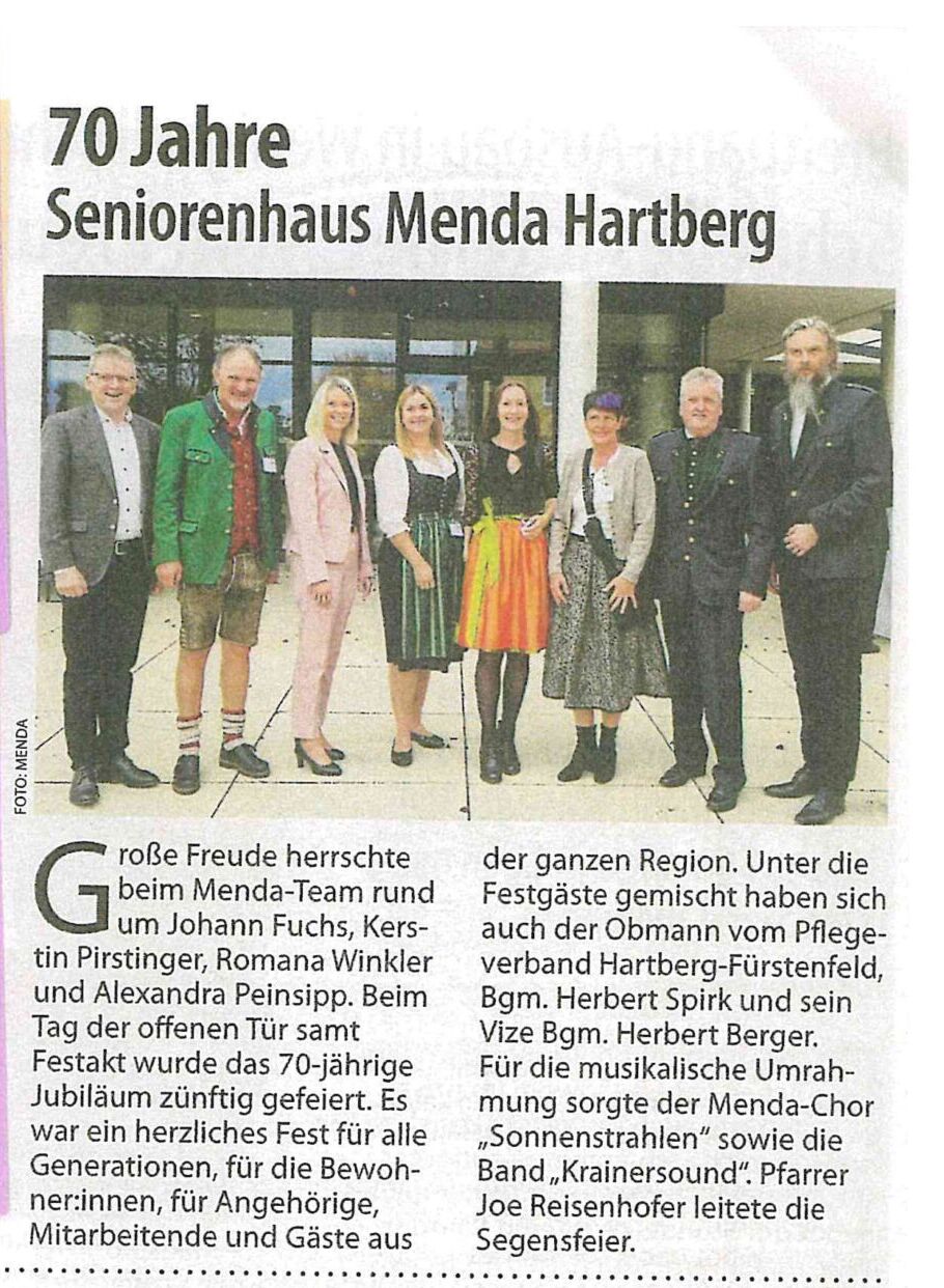 Eine Gruppe förmlich gekleideter Personen steht für ein Foto anlässlich des 70-jährigen Bestehens des Seniorenhauses Menda Hartberg zusammen, wie im nebenstehenden deutschen Zeitungsartikel beschrieben. Der linke Teil des Bildes ist durch violette Rechtecke verdeckt.