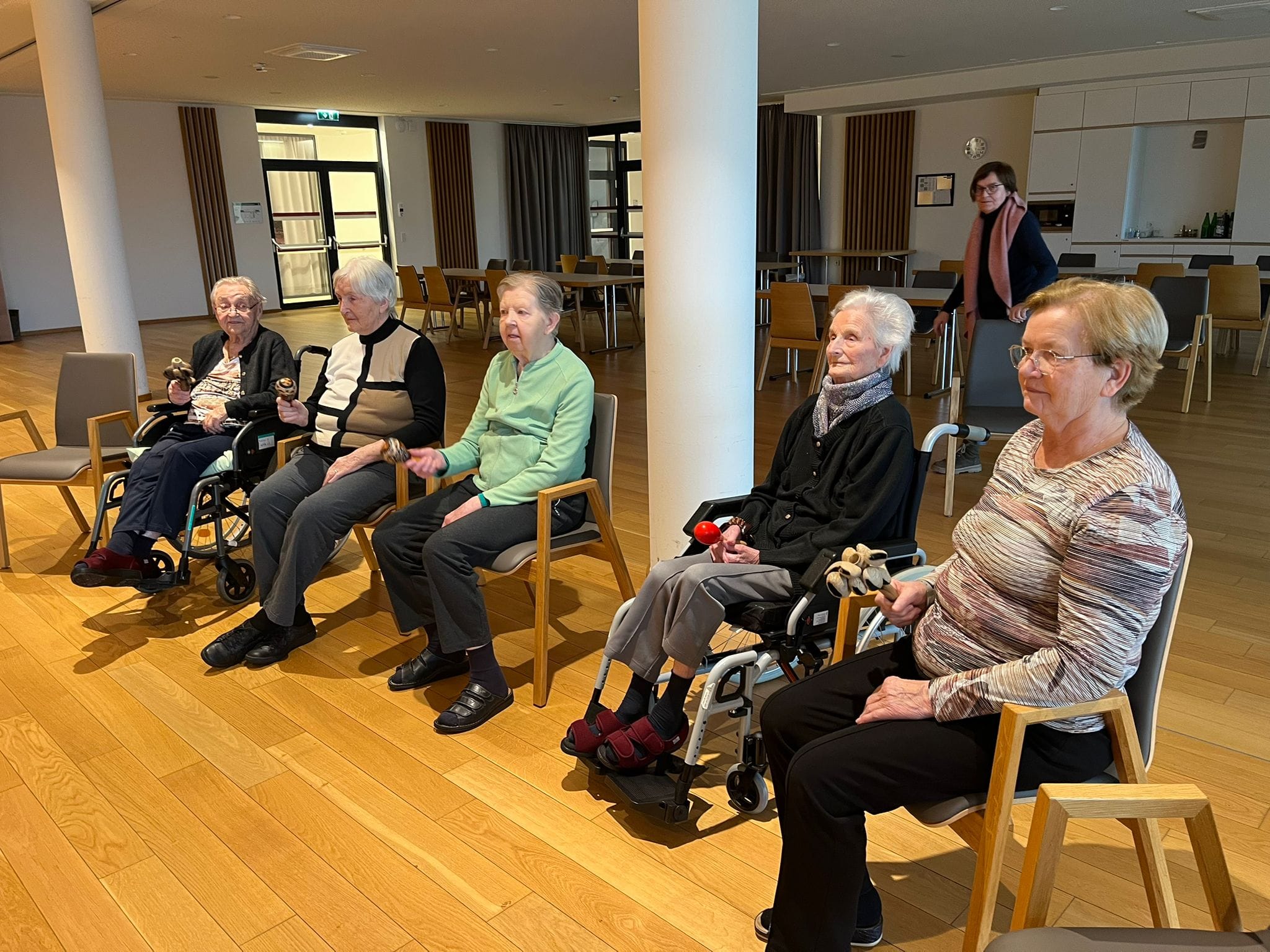 Bewohner sitzen im Kreis und nehmen an einer Aktivität im Seniorenhaus Menda teil