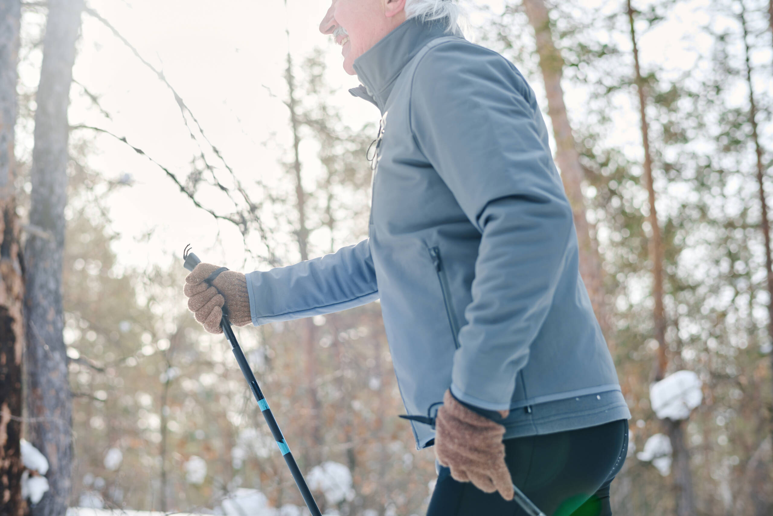 Seitenansicht, halber Ausschnitt eines älteren Mannes in Sportkleidung beim Spazieren am kalten Wintertag
