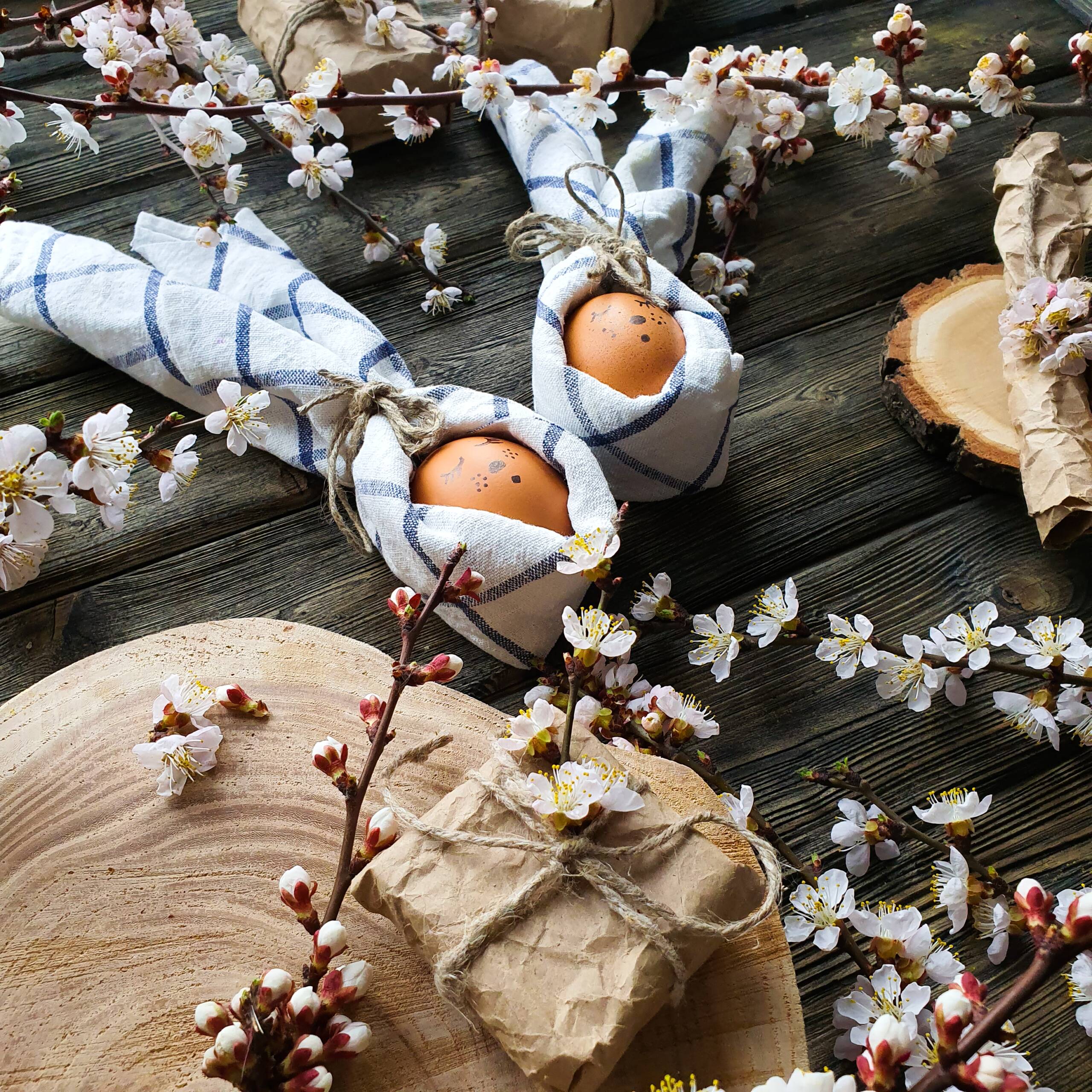 Osterei in einer Serviette in Form eines Hasen mit Blumen und Holzbrettern