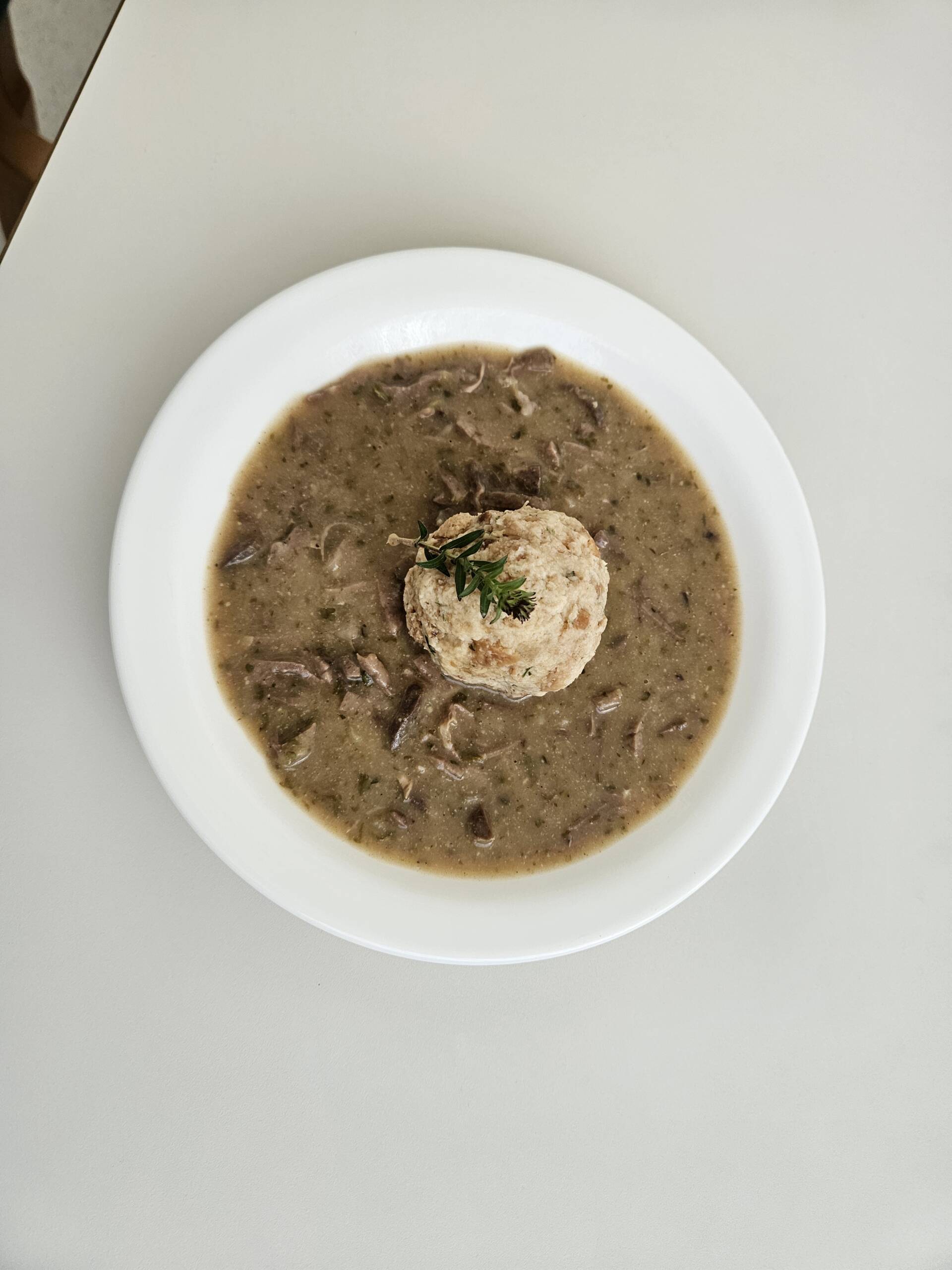 Herbstlich genießen: Saisonale Menüs bei Menda 5 Cremige Pilzsuppe mit Serviettenknödel und Thymianzweig, von oben fotografiert