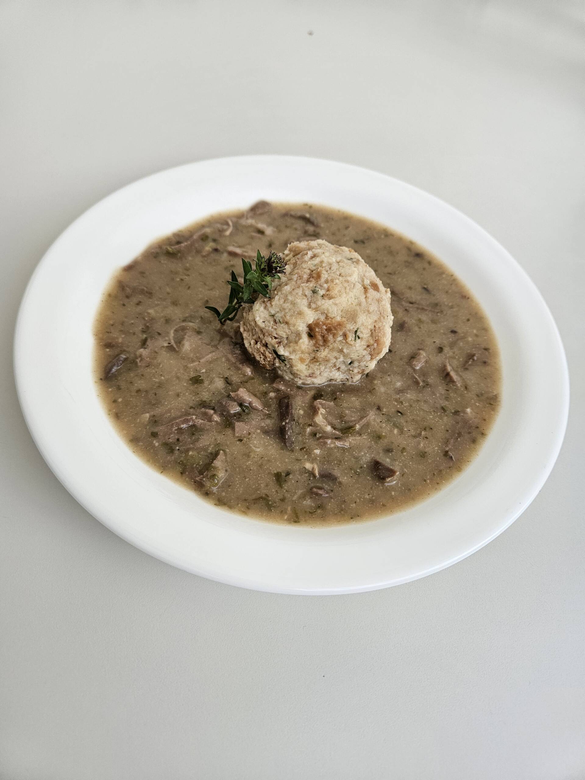 Herbstlich genießen: Saisonale Menüs bei Menda 3 Herbstliche Pilzcremesuppe mit Serviettenknödel, dekoriert mit frischem Thymian